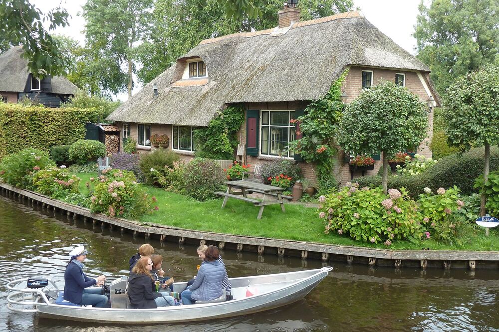 Een Gieterse gracht met rietgedekte huizen, bloeiende tuinen en een bootje op het water